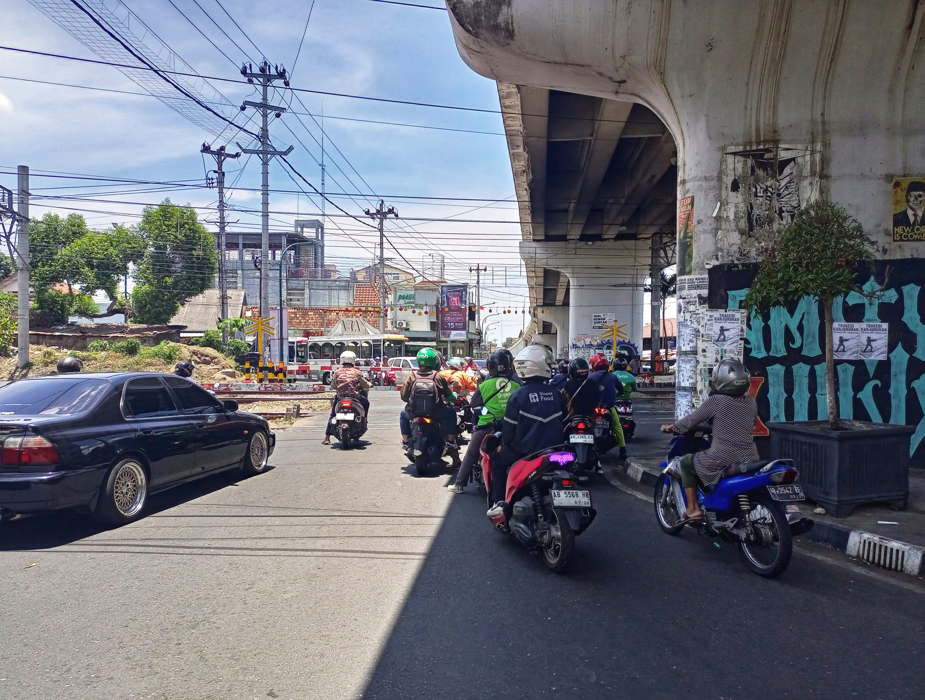 Sejumlah pengendara sepeda motor memilih untuk berteduh menghindari paparan panasnya sinar matahari saat berhenti di perlintasan kereta api Lempuyangan, Kota Jogja.