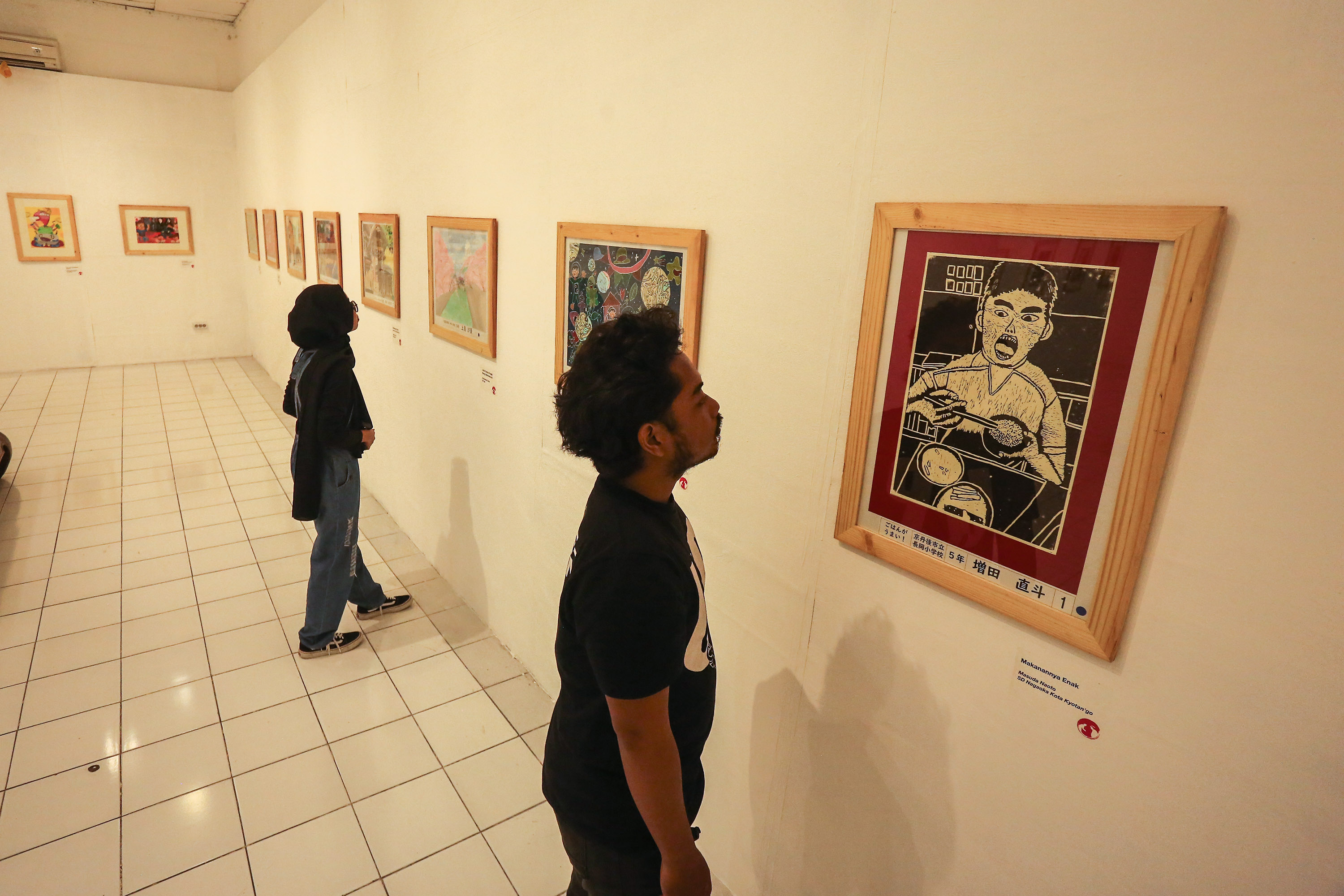 pengunjung mengamati karya lukisan peserta lomba lukis DIJ-Kyoto 2024 yang dipamerkan di Bentara Budaya Jogjakarta, Kota Baru, Gondokusuman, Jogja, Selasa (22/10). Lomba lukis DIJ-Kyoto yang telah ada sejak tahun1980an hingga kini menjadi sarana mengasah