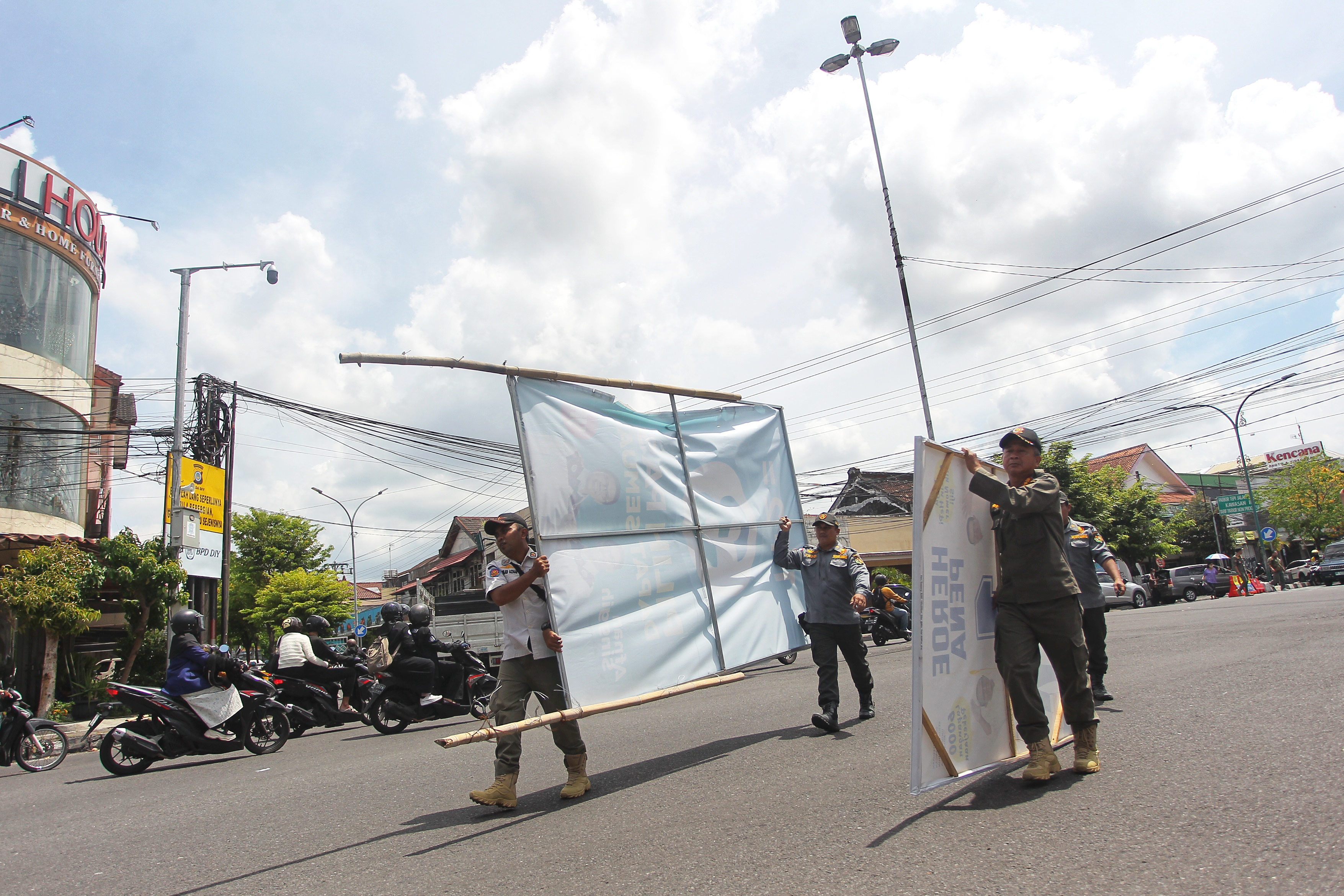 Personel Satpol PP menertibkan alat peraga kampanye pasangan calon peserta Pilkada Kota Jogja yang melanggar peraturan, di Simpang Empat Pingit, Kota Jogja, Rabu (23/10).