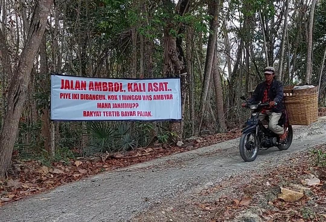 RUSAK: Banner berisi protes warga menghiasi jalan rusak di Banyuroto.&nbsp;