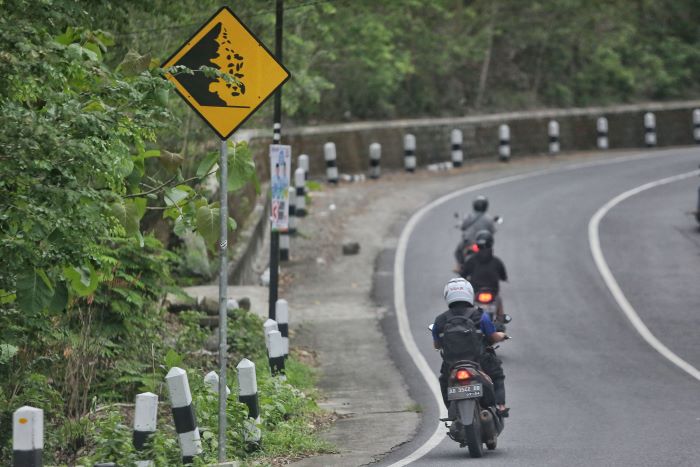 RAWAN LONGSOR: Kendaraan roda dua melintasi rambu bahaya tanah longsor di Jalan Imogiri-Dlingo, Wukirsari, Imogiri, Bantul Jumat (8/11/2024).