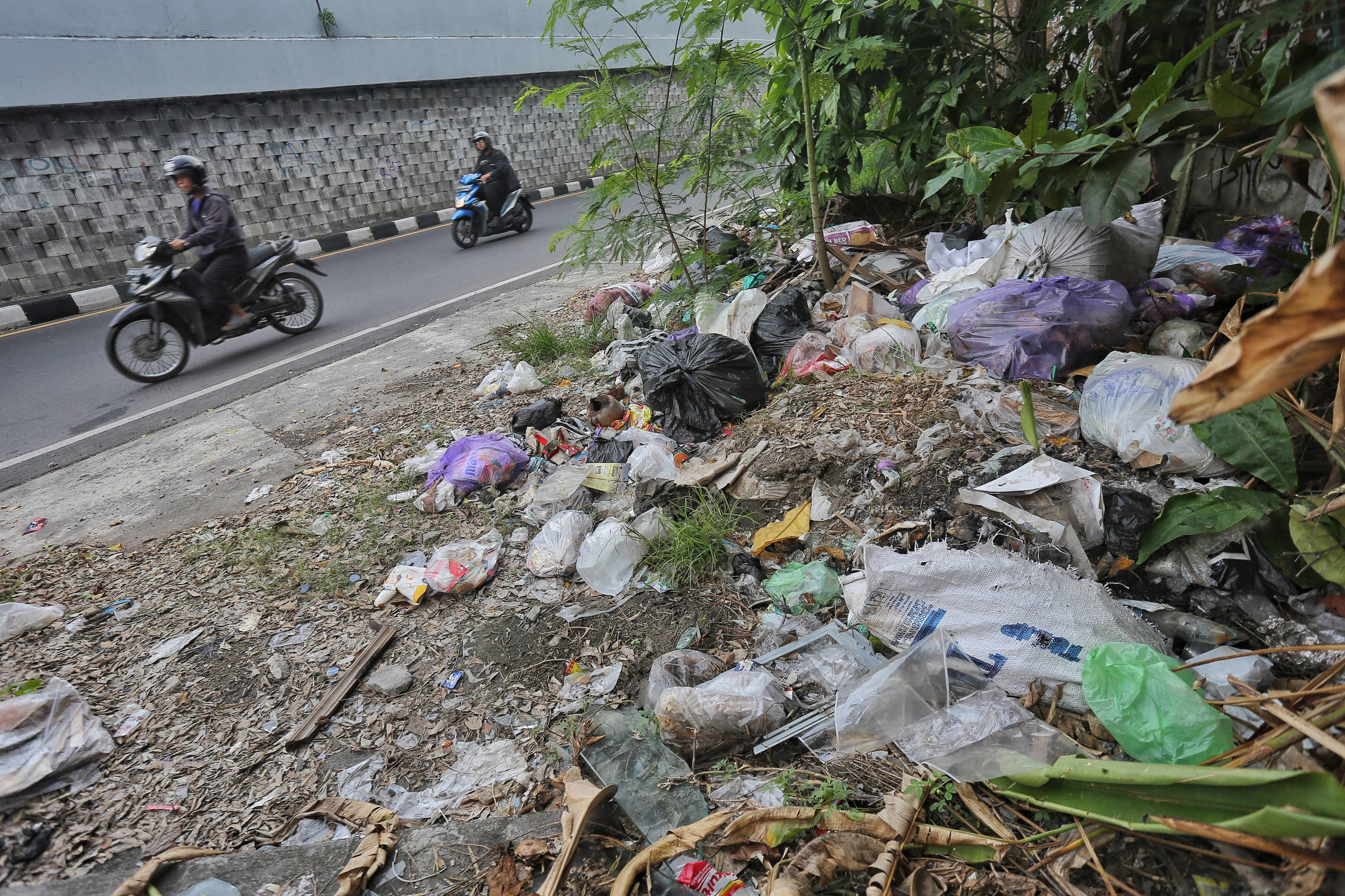 Warga melintas di salah  satu lokasi pembuangan sampah liar