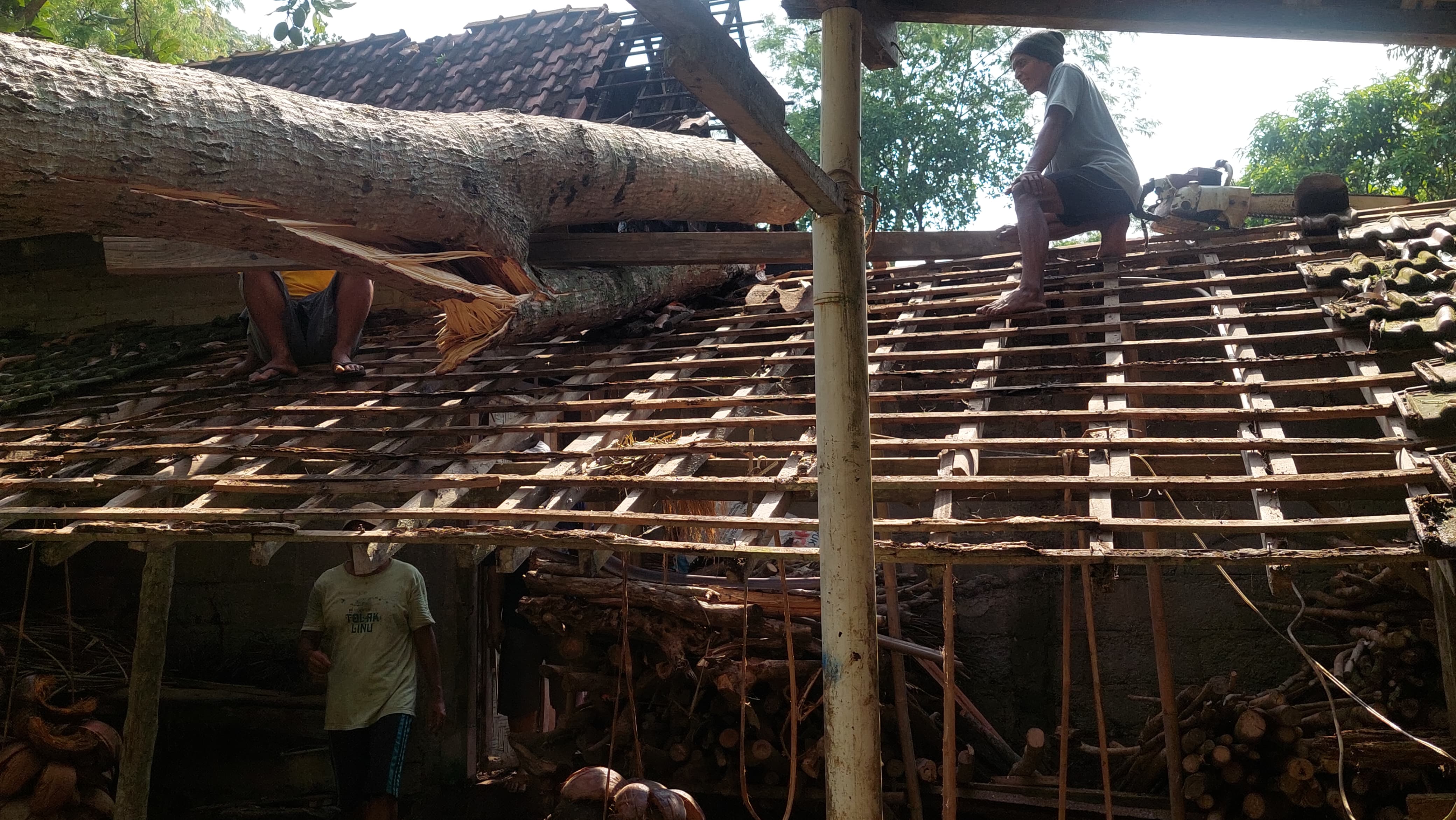 &nbsp;  RUSAK: Masyarakat memotong sisa batang yang masih menimpa rumah.