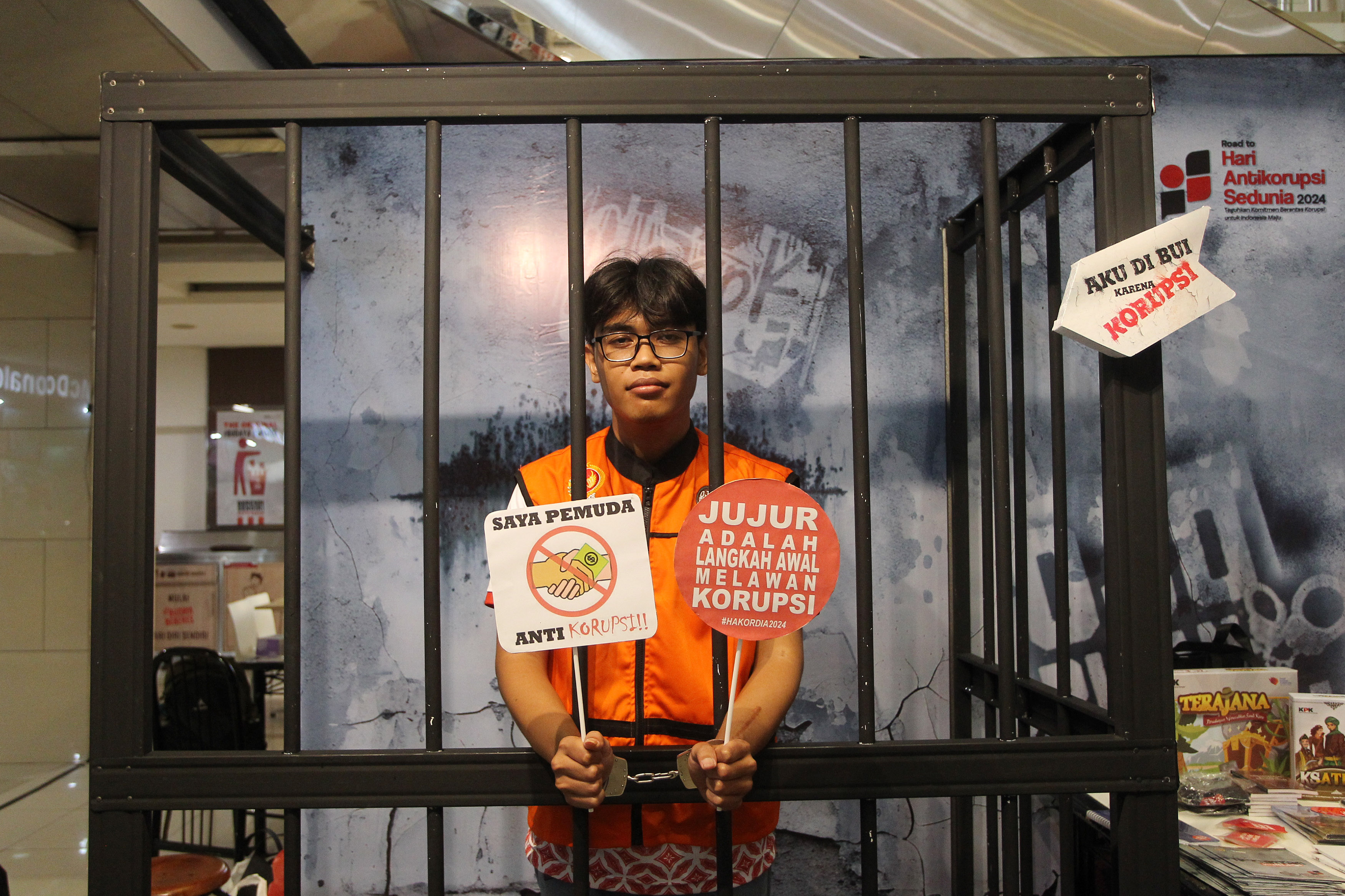 Pengunjung mencoba berada di dalam stand menyerupai sel tahanan korupsi dan mengenakan rompi oranye dalam rangkaian kegiatan hari Antikorupsi Sedunia (Hakordia), di Galeria Mall, Minggu (24/11).