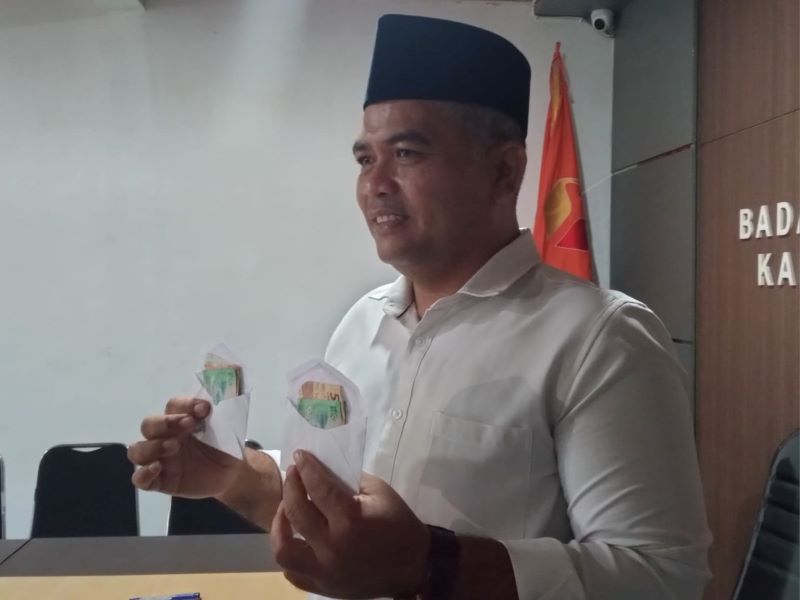 BAGI AMPLOP: Ketua Bawaslu Kabupaten Magelang menunjukkan amplop berisi uang yang dibagikan kepada warga saat masa tenang Pilkada 2024.&nbsp;