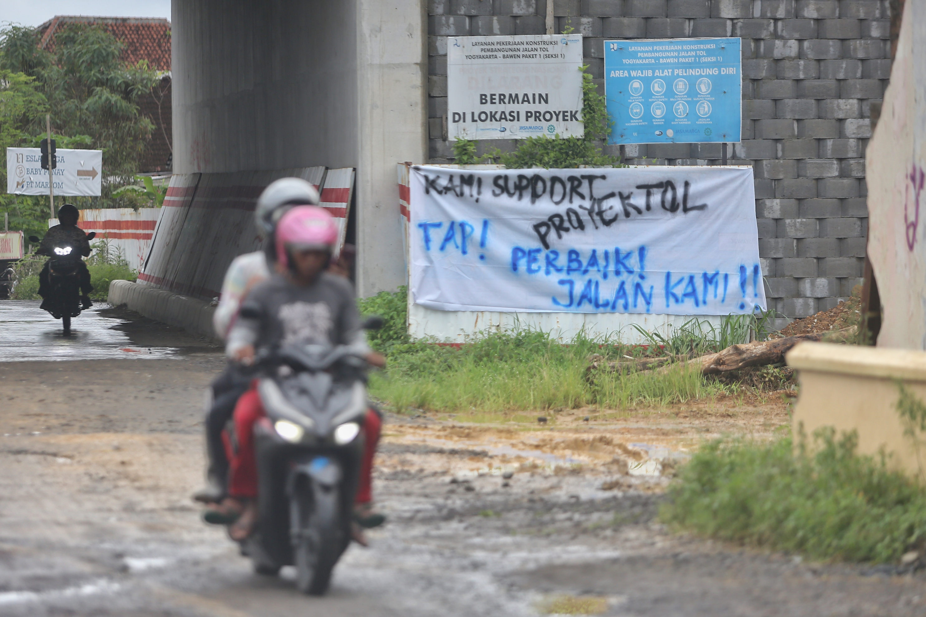 Warga melintas di jalan yang rusak akibat proyek tol Jogja- Bawen di Pundong, Tirtoadi, Mlati, Sleman.