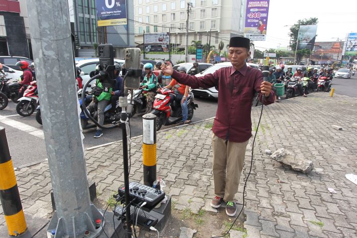 PERCAYA DIRI: Amin Ashari saat ngamen online di simpang empat Condongcatur, Sleman.