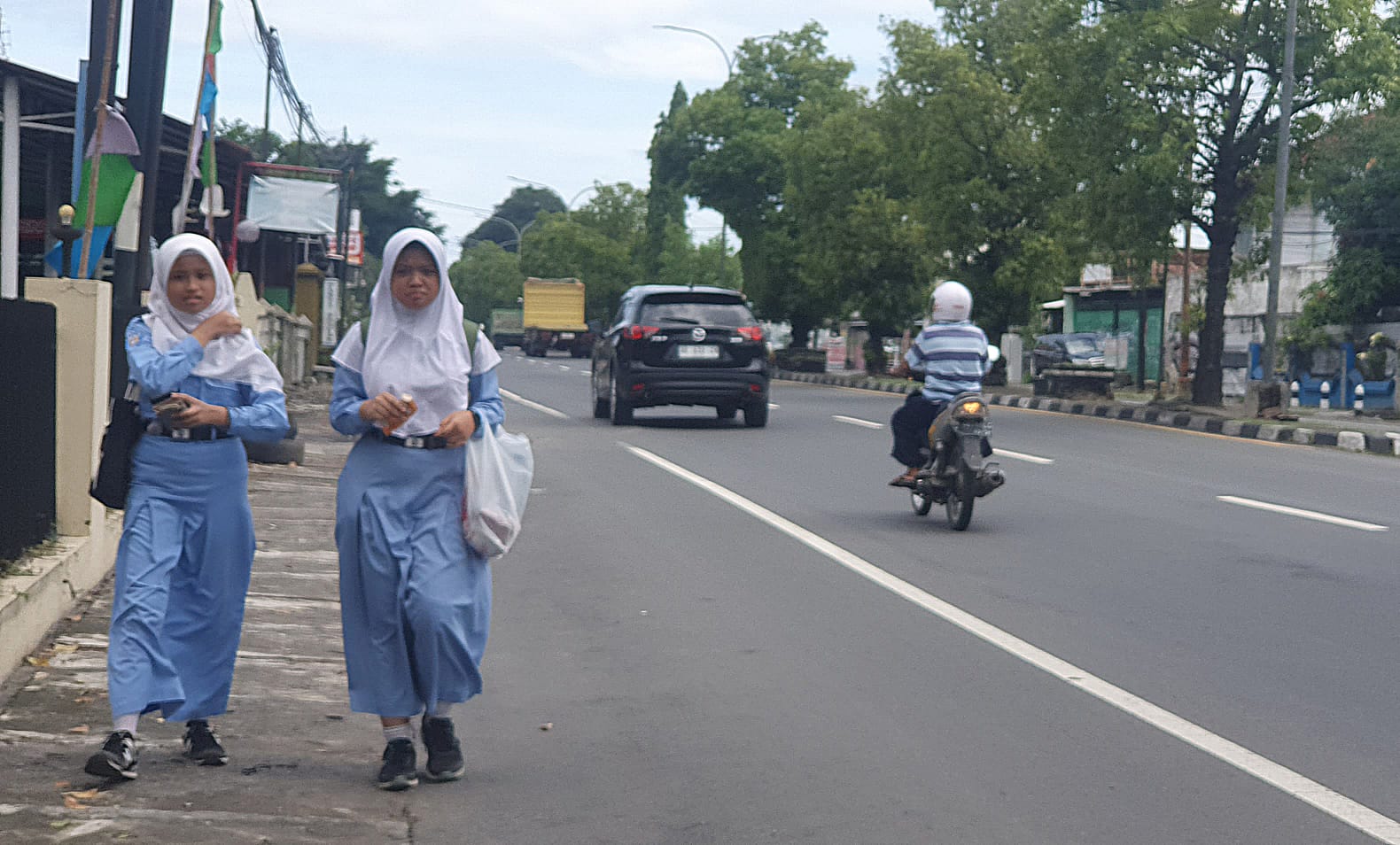 ANAK BANGSA - Dua siswi SMP 1 Kalasan, Sleman nampak berjalan menyusuri trotoar jalur jalan Joga-Solo pada Jumat (29/11/2024)  (GUNAWAN/Radar Jogja)