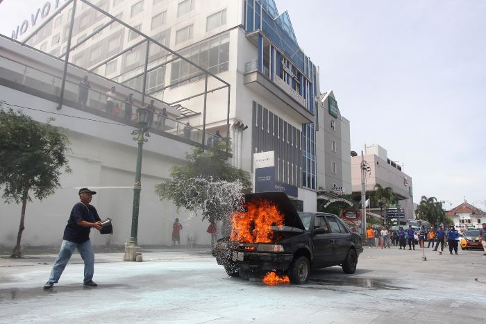 Relawan berusaha memadamkan api yang membakar kendaraan mobil saat simulasi penanganan kebakaran di Jalan Perwakilan, kawasan Malioboro, Kota Jogja, Senin (9/12/2024).