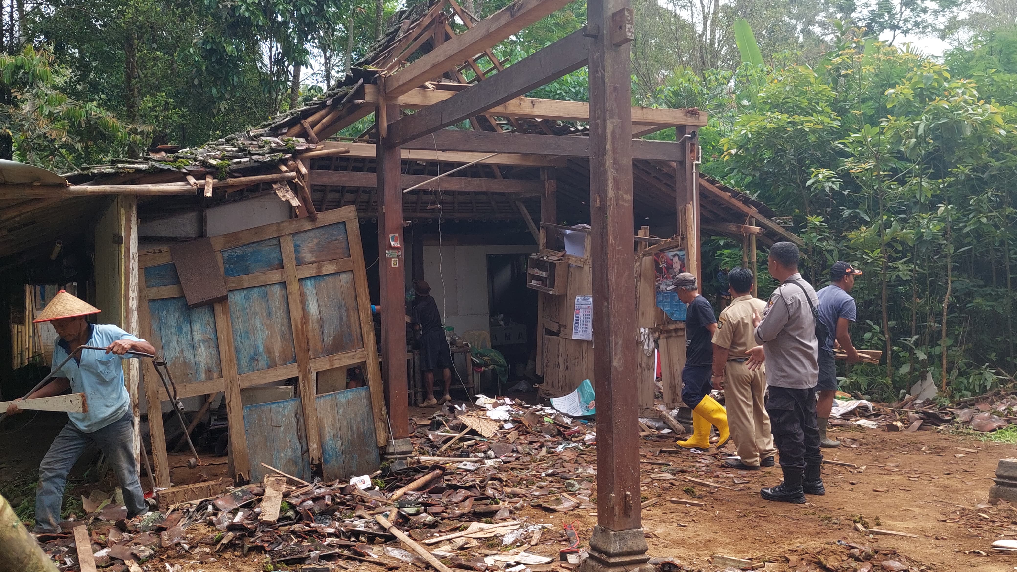 EVAKUASI: Warga dan tokoh masyarakat bergotong royong membersihkan puing bangunan rumah Nardi yang tertimpa pohon.