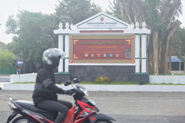 Seorang pengendara motor melintas di depan papan Kalurahan Sardonoharjo, Ngaglik, Sleman, kemarin (11/12). Mulai tahun depan setiap kalurahan/ kelurahan se-DIY menerima tambahan dana Rp 100 juta
