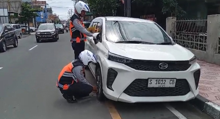 DIGEMBOSI: Petugas Dishub Kota Jogja&nbsp; melakukan penggembosan terhadap ban dari kendaraan yang melanggar aturan parkir di Jalan Pasar Kembang, kemarin(26/12).