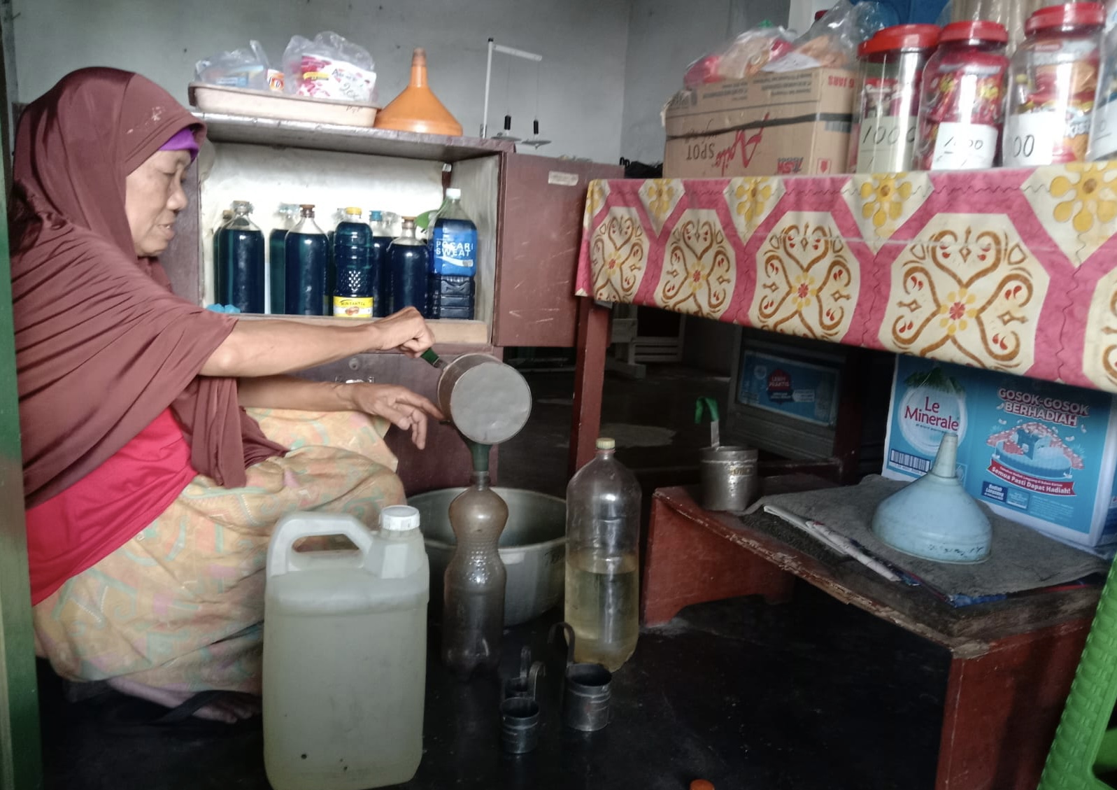 AGUNG DWI PRAKOSO/RADAR JOGJA  BARANG JADUL: Tri Sarjimah sedang menakar minyak tanah dengan canting literan untuk dijual di warung kelontong miliknya, Jumat (3/1).