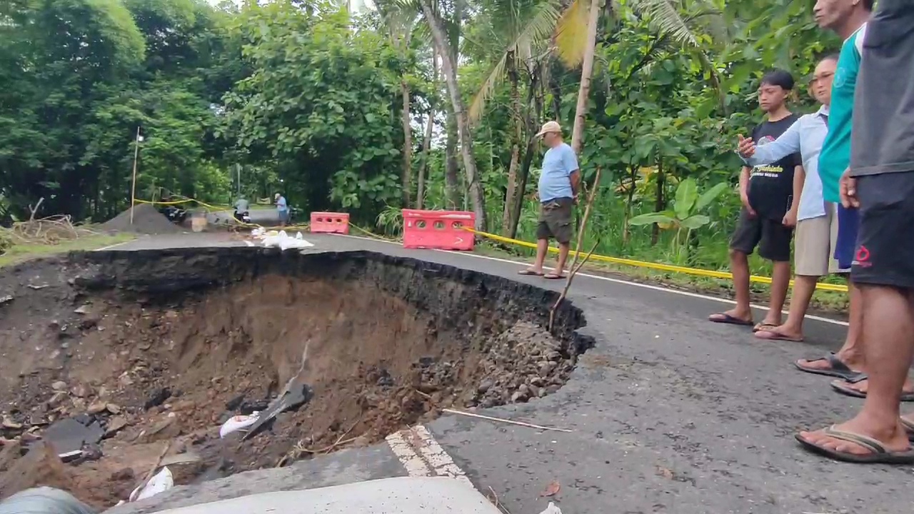TAK BISA DILEWATI: Warga melihat kondisi jalan provinsi Sentolo-Nanggulan yang longsor akibat tergerus air kemarin (5/1).