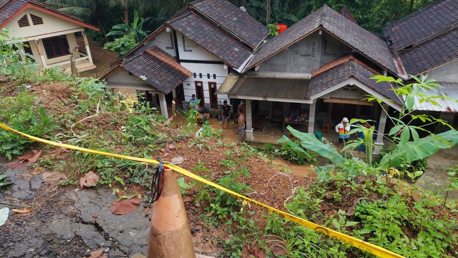 KERJABAKTI: Warga membersihkan sisa meterial longsor yang mengenai rumah.