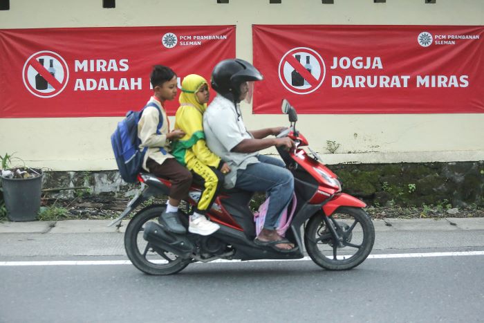 MASIH MARAK: Warga melintasi spanduk tolak miras di Jalan Prambanan-Piyungan, Bokoharjo, Prambanan, Sleman Selasa (7/1/2025).