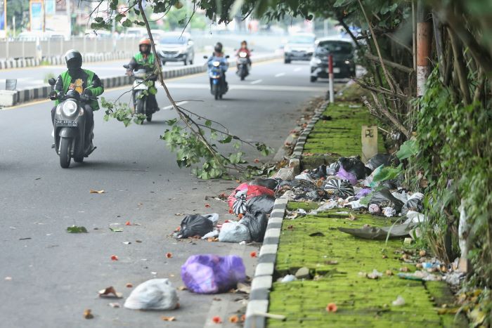 BERSERAKAN: Pengendara motor melintasi tumpukan sampah liar di ring road utara, Sinduadi, Mlati, Sleman Kamis (9/1/2025).