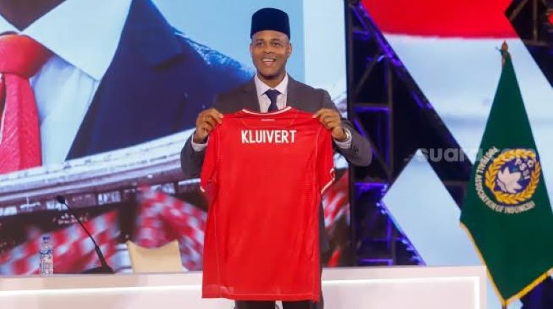 Patrik kluivert yang mengenakan peci hitam menunjukan nama belakang pada baju jesry timnas.