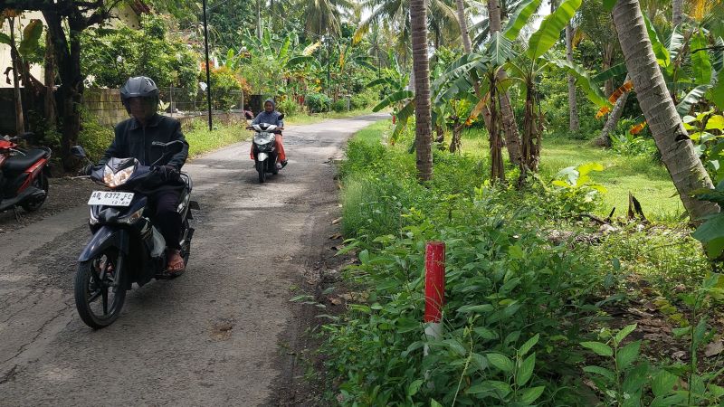 DILANJUTKAN: Warga melintasi patok yang berada di sisi jalan menuju Kalurahan Kulur.