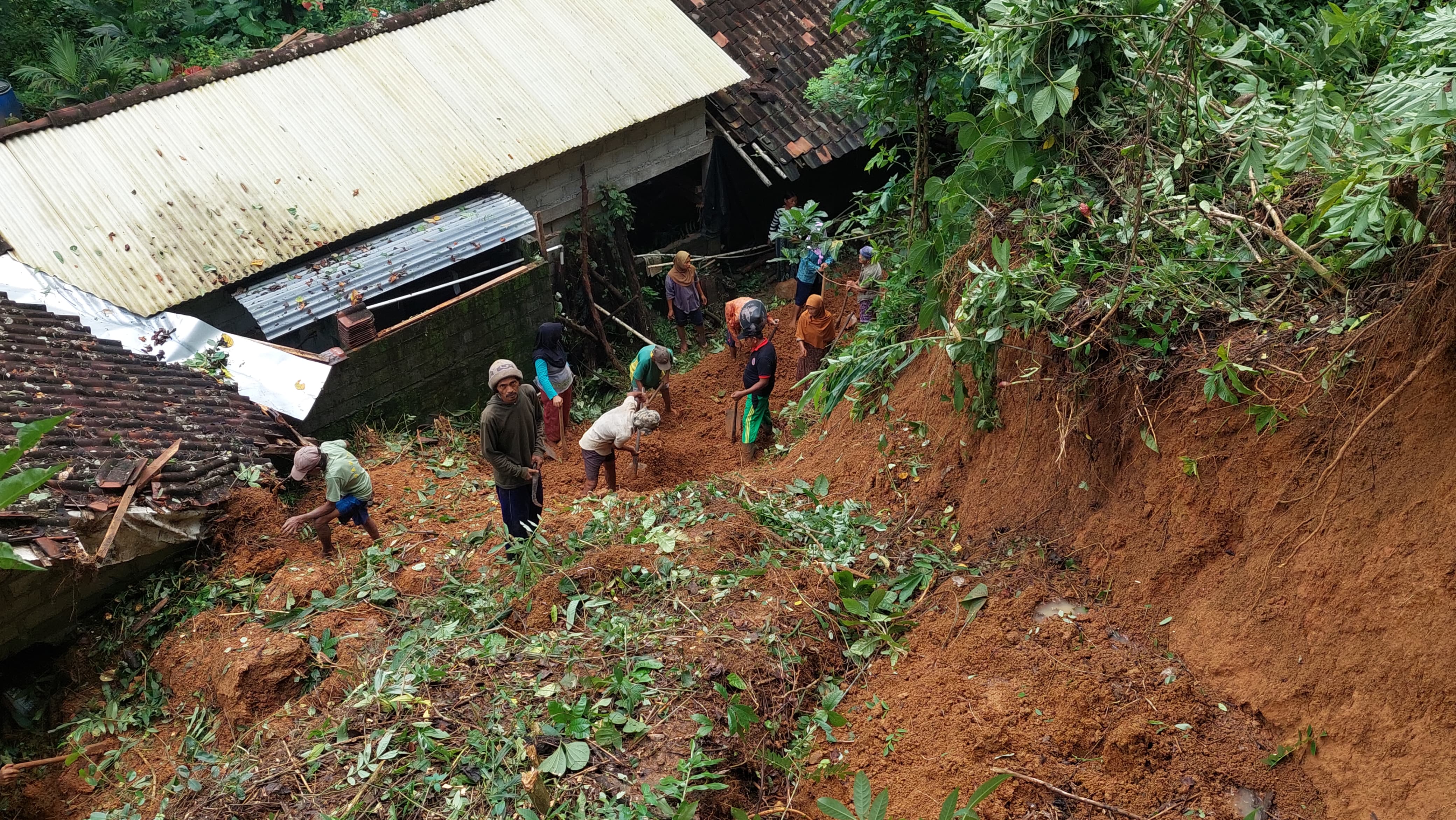 RUSAK: Warga membersihkan material longsor yang menghantam rumah Shaleh.&nbsp;