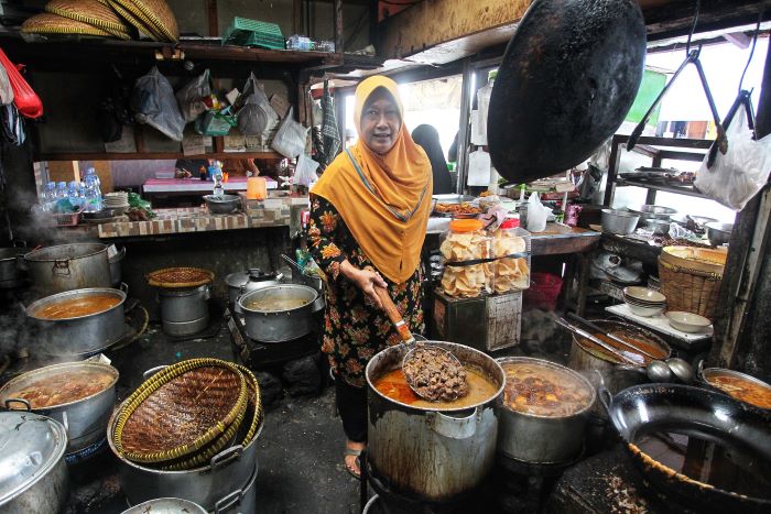 LEGEND: Pemilik Warung Brongkos Handayani Tri Suparmi saat meladeni para pelanggan. Tempat makan ini akan segera berpindah menyusul uji coba penutupan Plengkung Gading.