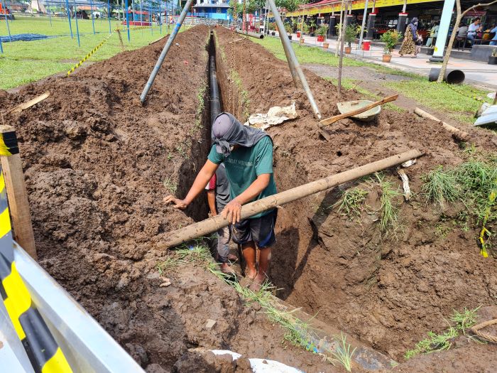 GOTONG ROYONG: Beberapa pekerja tampak memperbaiki pipa saluran air yang berada di Alun-alun Kota Magelang.