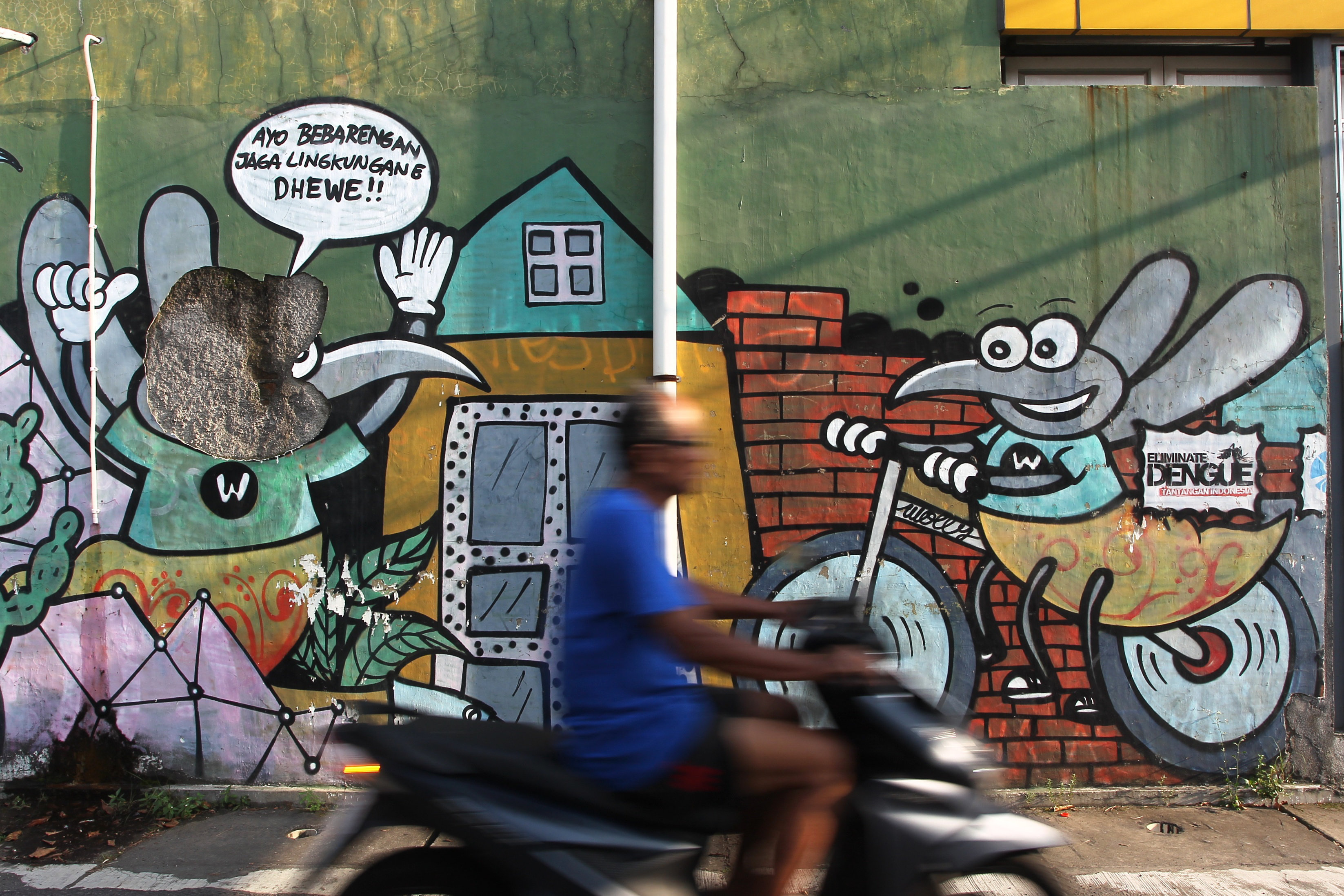 Pengguna jalan melintas di dekat mural bergambar nyamuk di kawasan Sorosutan, Umbulharjo, Kota Jogja, kemarin (5/2).