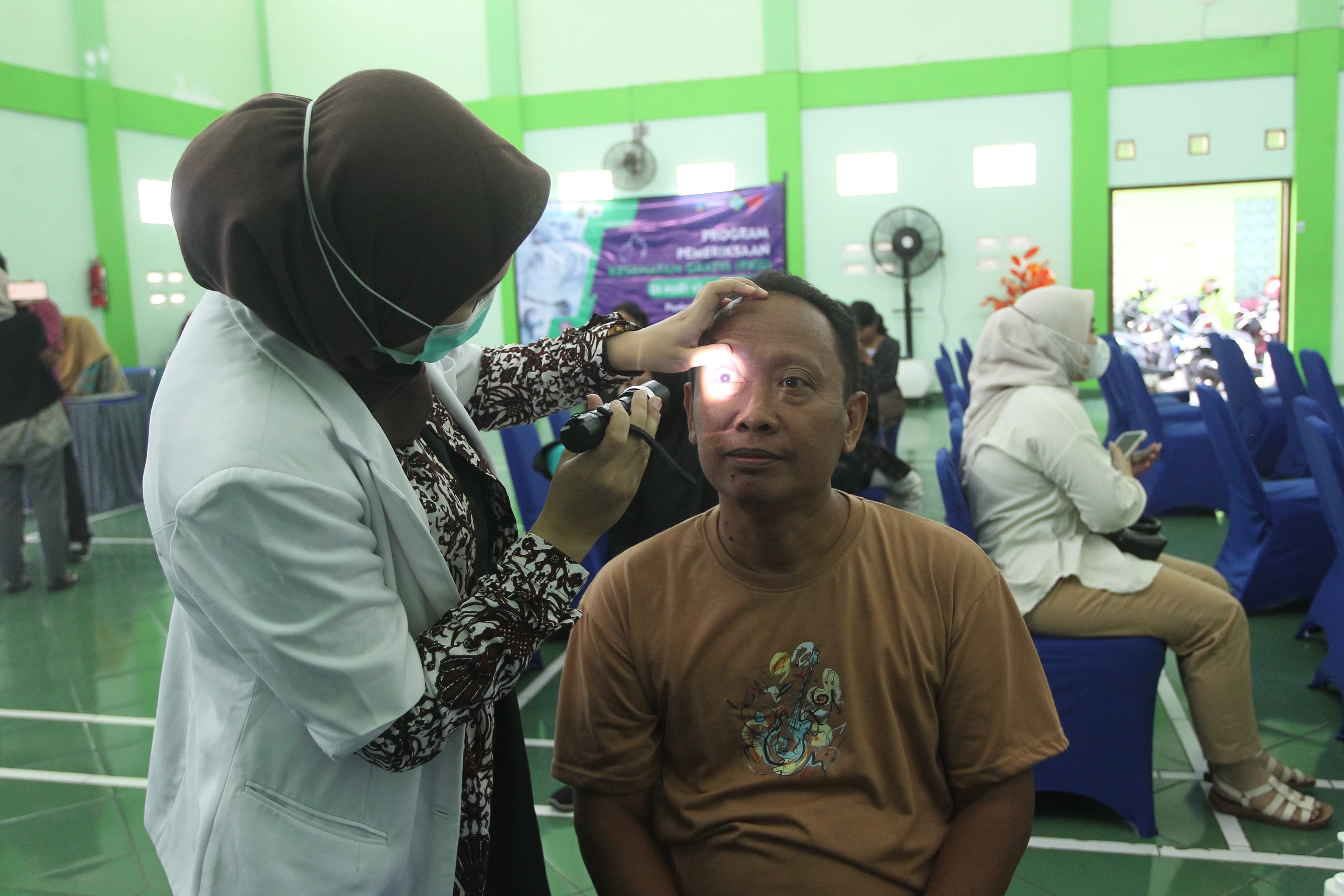 Dokter memeriksa mata pasien saat berlangsung pemeriksaan kesehatan gratis di Gedung Serbaguna Kelurahan Wirogunan, Kota Jogja, Selasa (11/2/2025).