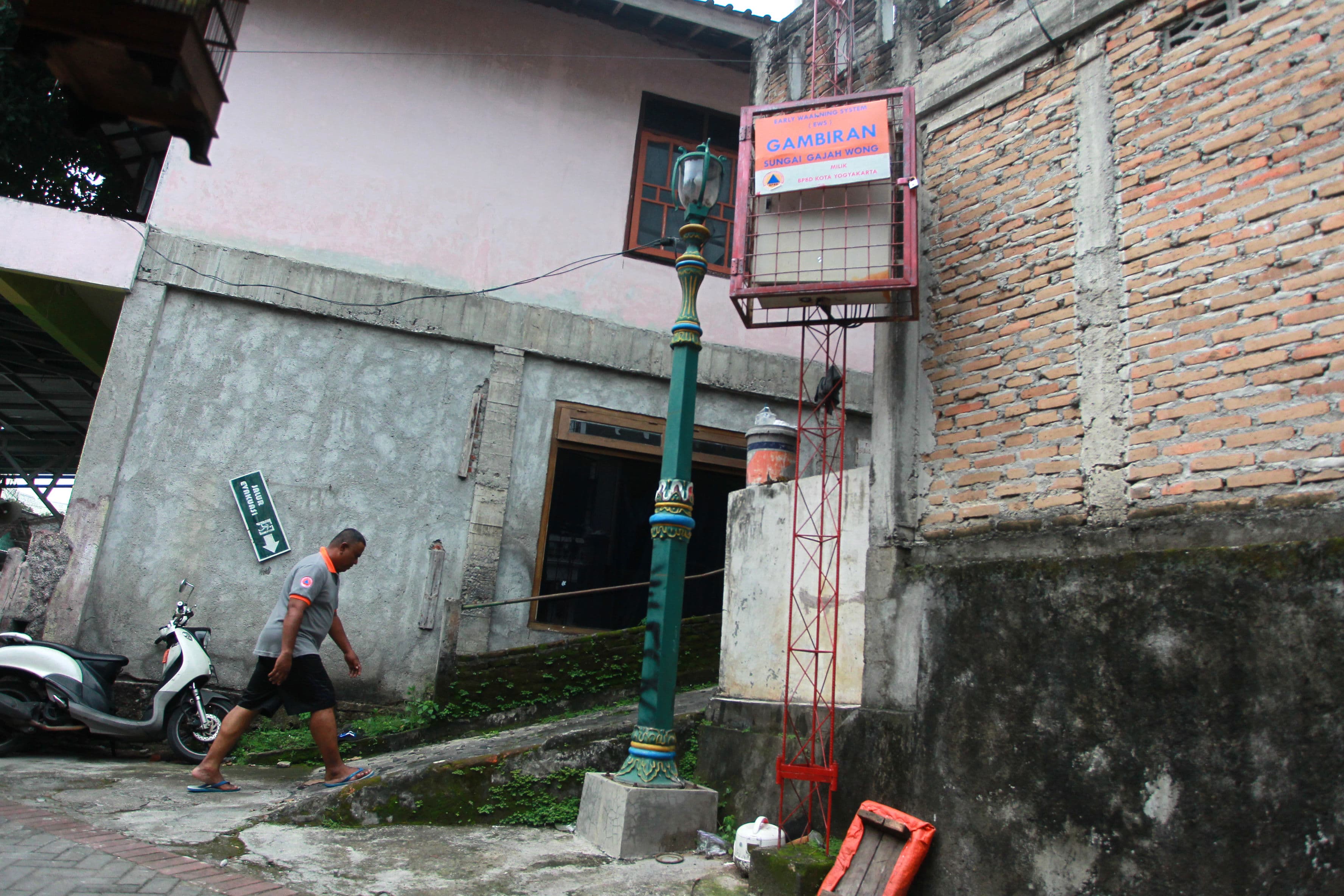 Warga melintas di dekat Early Warning System (EWS) banjir yang terpasang di bantaran Sungai Gajah Wong, Kampung Gambiran, Pandeyan, Umbulharjo, Kota Jogja.