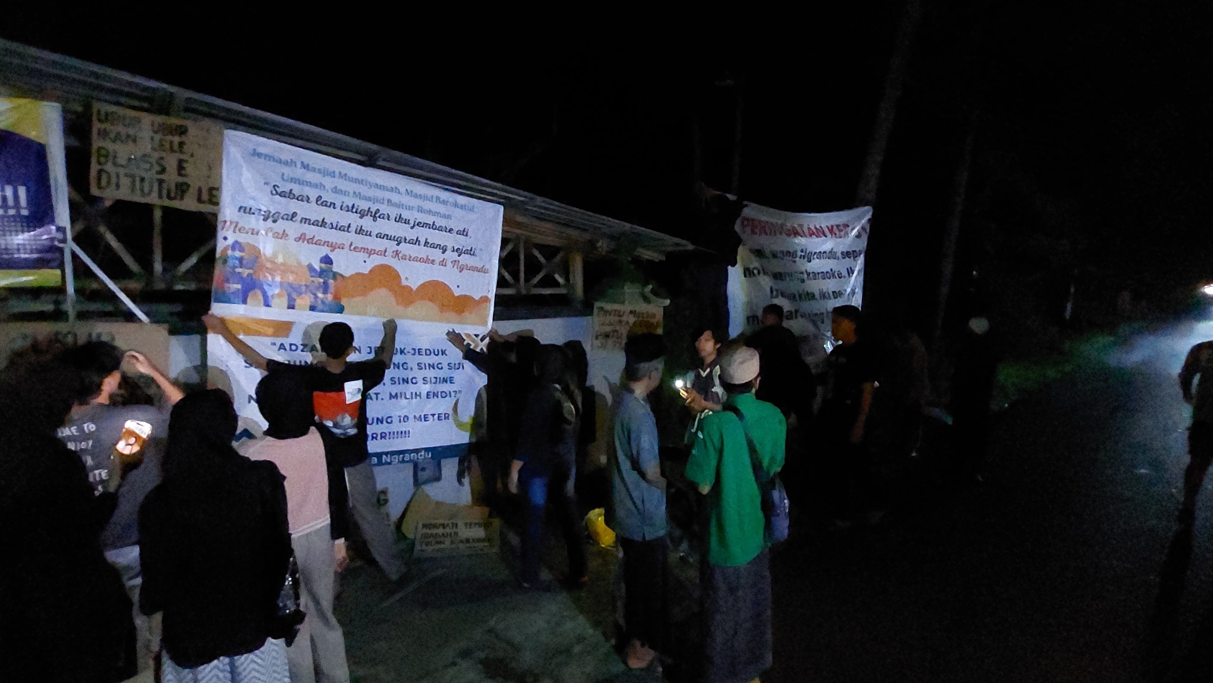 PENOLAKAN: Warga memasang banner sebagai tanda menolak adanya tempat karaoke di Triharjo, Wates, Sabtu (15/2/2025) malam.
