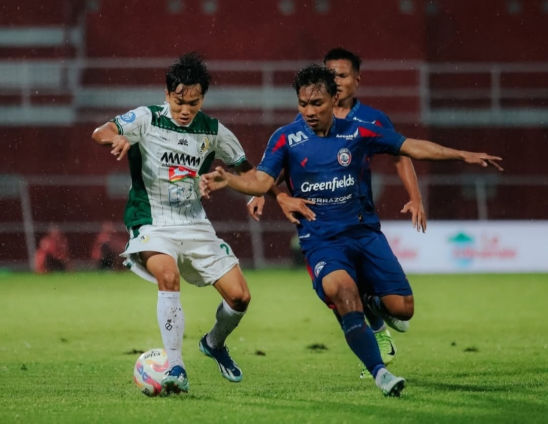 Pemain PSS Sleman, Dominicus Dion (putih) coba mengusai bola dari hadangan pemain Arema (biru) (PSS Sleman)