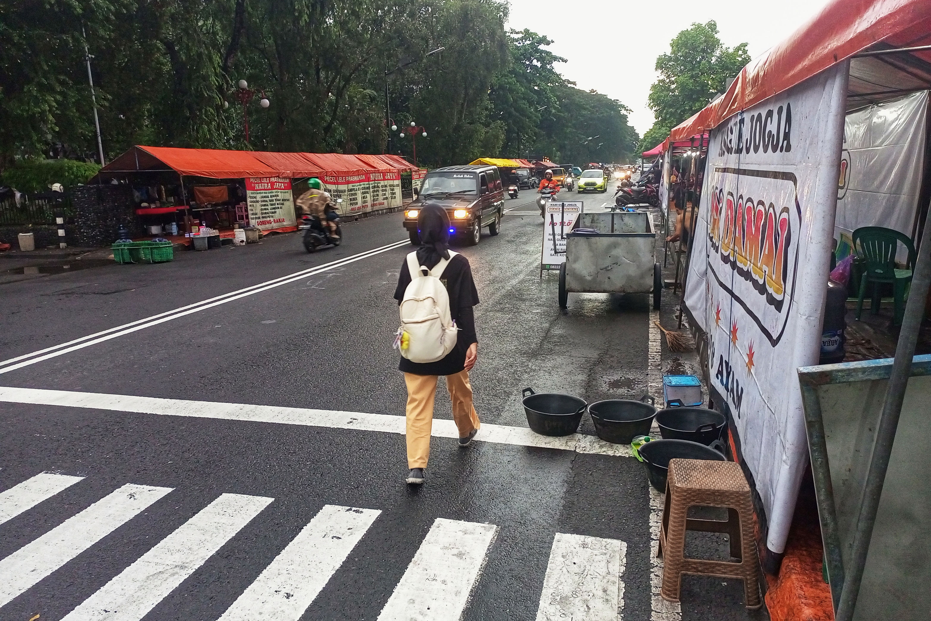 Pejalan kaki terpaksa berjalan di badan jalan karena trotoar di Jalan Persatuan, Depok, Sleman, digunakan PKL kuliner untuk berjualan, kemarin (27/2). Keberadaan mereka dikeluhkan oleh sebagian masyar