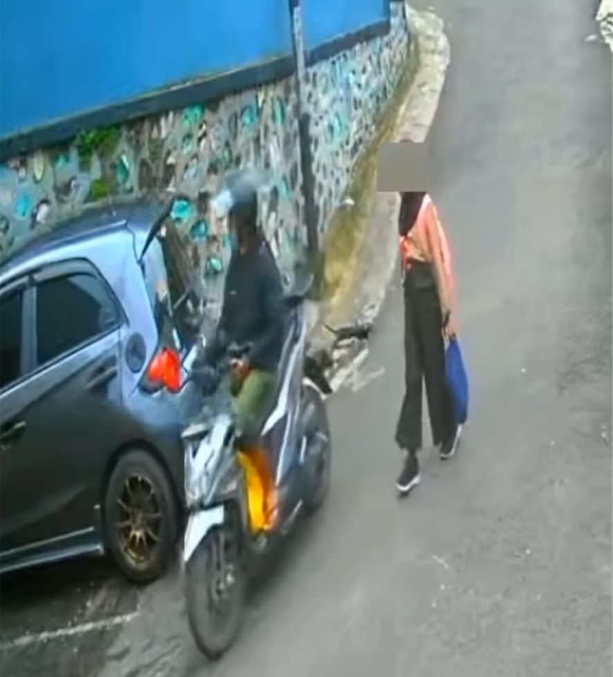 Tampak seorang pria mengendarai motor melintas di depan anak sekolah yang sedang berjalan kaki.
