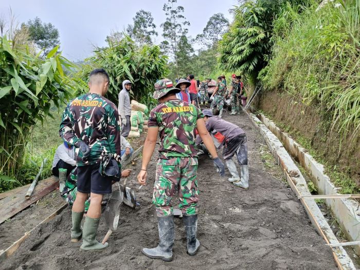 GOTONG ROYONG: Personel satgas TMMD bersama warga Desa Wonolelo saat melakukan pengecoran jalan Minggu (2/3).