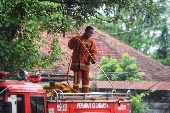 BELUM MAKSIMAL: Petugas pemadam kebakaran saat menggulung selang usai memadamkan api. Di Sleman, pemadaman masih belum maksimal karena petigas memiliki waktu tanggap lebih dari 15 menit.