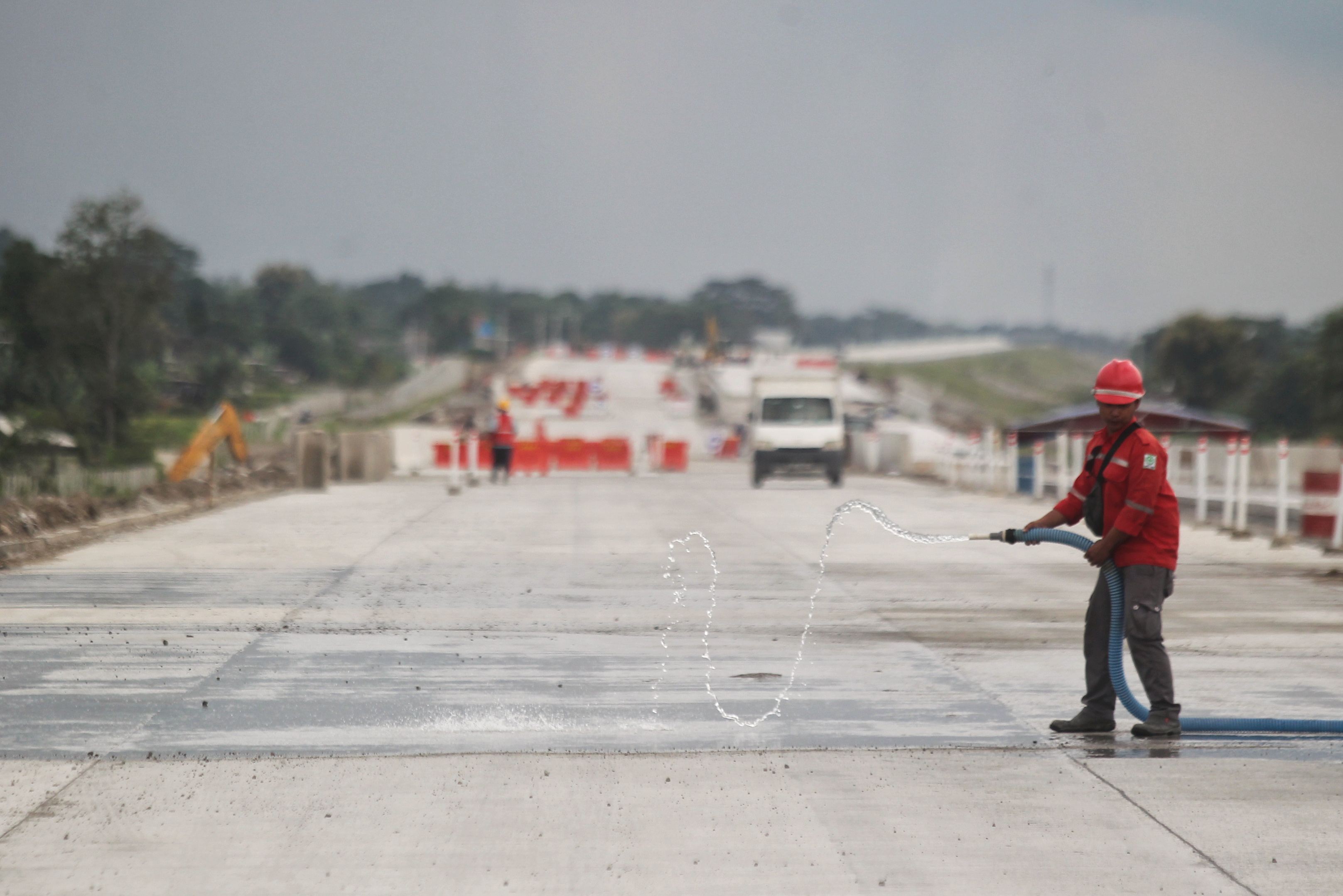 Pekerja membersihkan beton dari bebatuan dengan cara menyemprotkan air di area pembangunan jalan Tol Solo-Jogja ruas Prambanan-Kalasan, di Kalurahan Tamanmartani, Kapanewon Kalasan, Sleman