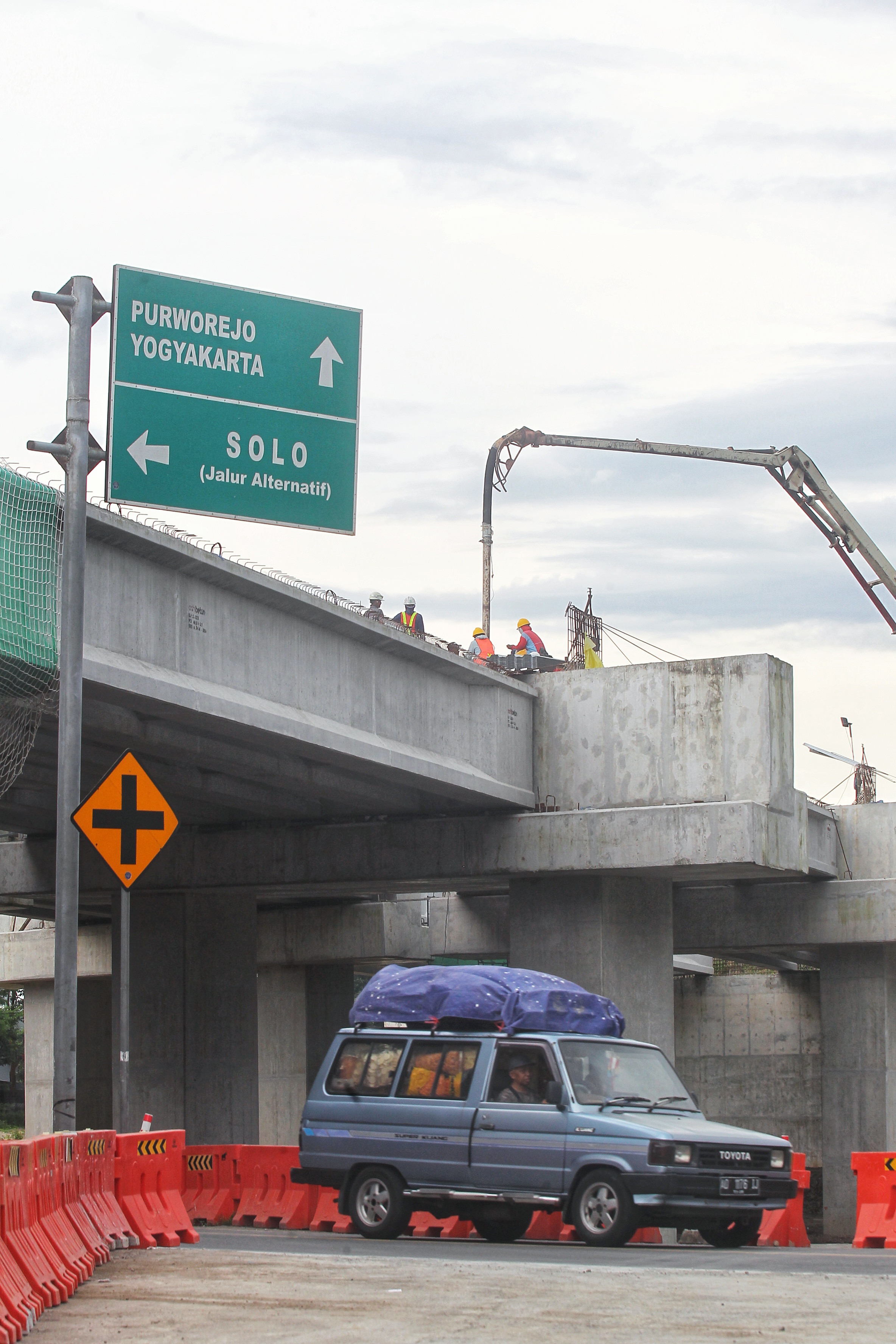 Pekerja membersihkan beton dari bebatuan dengan cara menyemprotkan air di area pembangunan jalan Tol Solo-Jogja ruas Prambanan-Kalasan, di Kalurahan Tamanmartani, Kapanewon Kalasan, Sleman