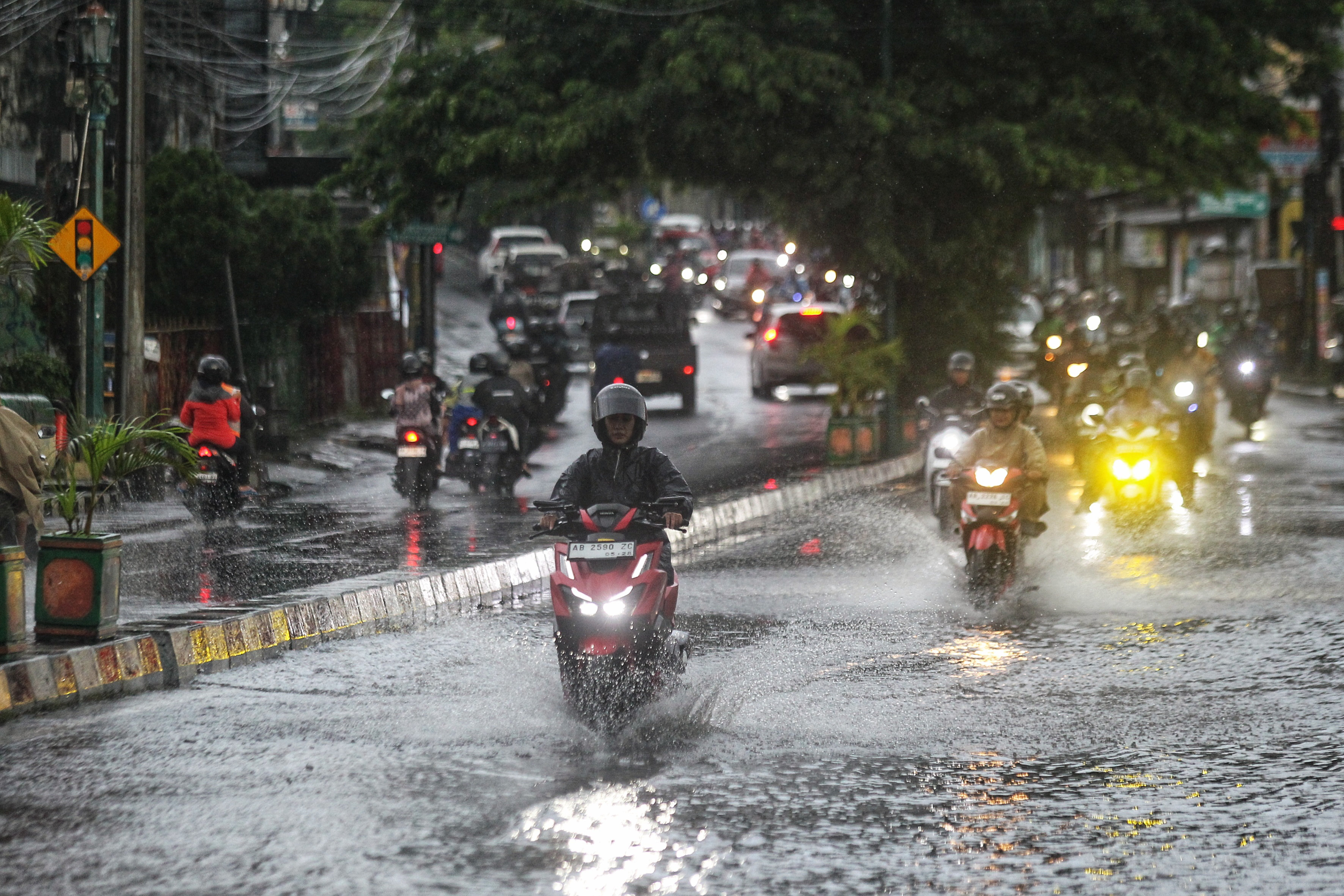 Pengendara kendaraan bermotor menerjang genangan air hujan di jembatan yang melintang di atas Sungai Winongo, Jalan Kyai Mojo, Kota Jogja, Selasa (11/3)