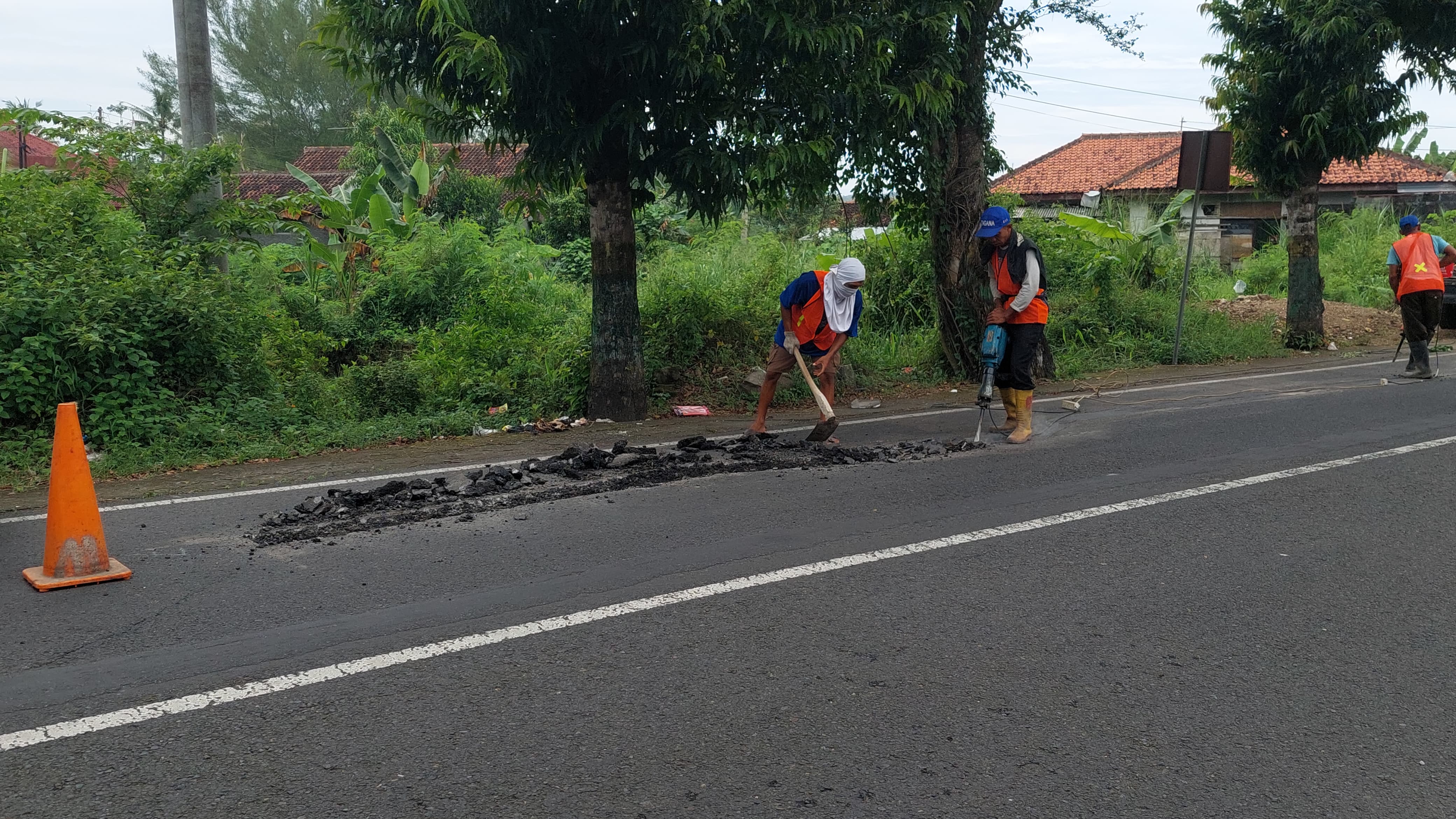 TAMBAL JALAN: Pekerja melakukan perbaikan jalan menjelang mudik lebaran.