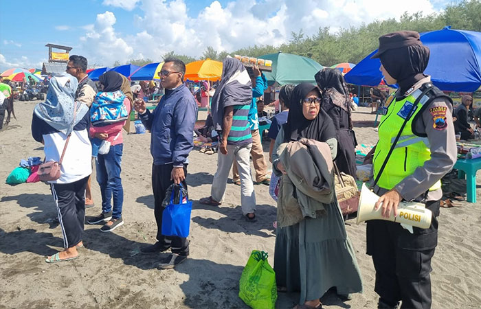 PATROLI : Polwan dari Polres Kebumen memberikan imbauan melalui pengeras suara agar wisatawan tak nekat mandi di laut.