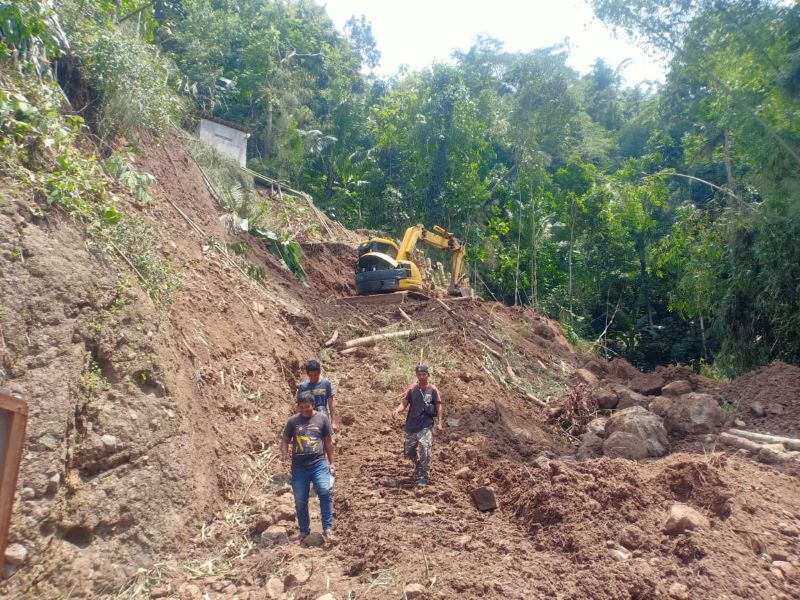 LONGSOR: Personel BPBD melakukan pemindahan material yang menutup jalan.&nbsp;