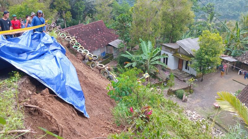 AMBROL: Dinding tanah di jalan kabupaten amblas setelah diguyur hujan kini ditutup terpal.