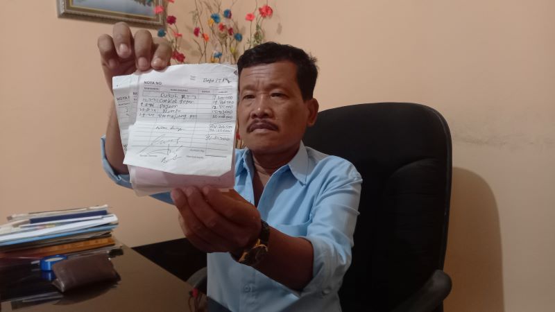 TUNJUKKAN BUKTI: Lurah Seloharjo Marhadi Badrun saat ditemui di ruangannya sambil menunjukan kuitansi pembayaran yang dituduhkan belum terbayarkan oleh massa aksi.