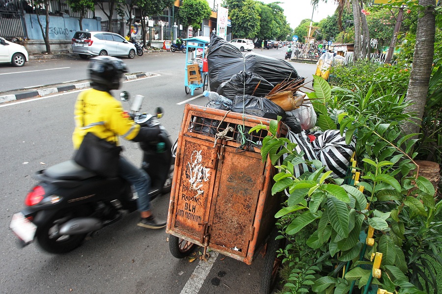 Pengguna jalan melintas di dekat gerobak berisi sampah di kawasan Lempuyangan, Kota Jogja, Minggu (20/4/2025).
