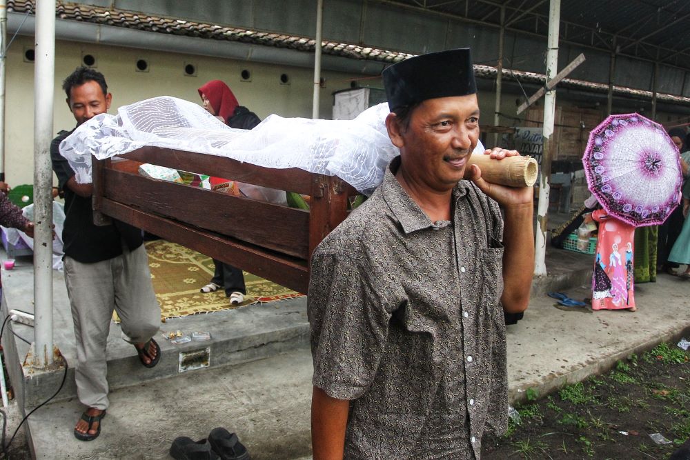 warga saat mengangkat jodang dengan beragam isian untuk upacara adat
