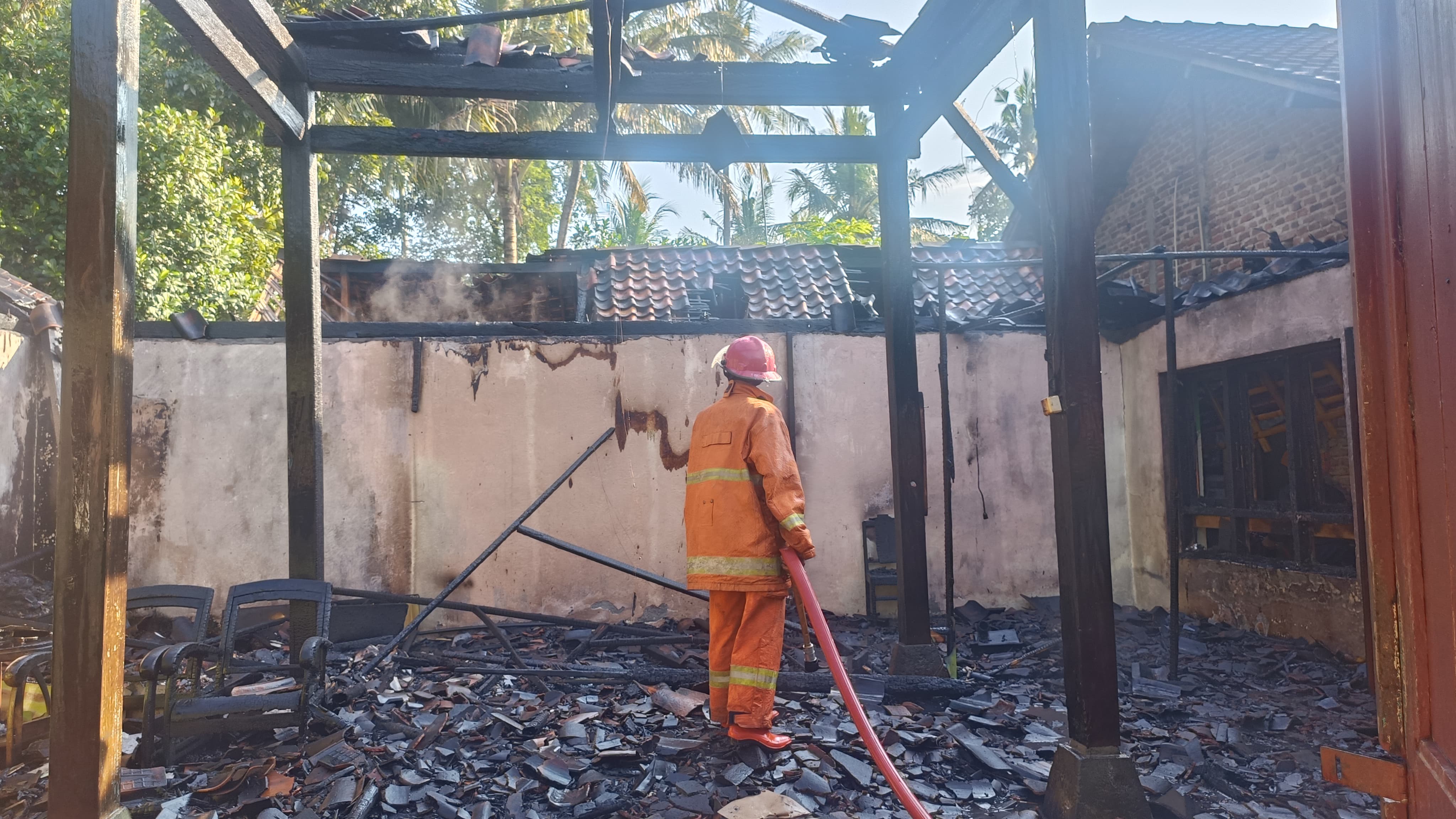 SISA PUING-PUING: Petugas Damkar Kulon Progo berusaha memadamkan api di sisa-sisa bangunan rumah Widodo di Nanggulan, Kulon Progo.