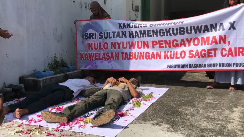 TAGIH: Nasabah BUKP Wates melakukan aksi tutup mulut dan tiduran di depan kantor pelayanan.&nbsp;