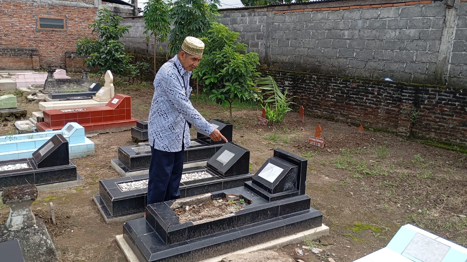 RUSAK : Ketua RW. 04 Kampung Basen, Purbayan, Kotagede Wahyono saat menunjukkan makam yang dirusak orang tidak dikenal pada Senin (19/5/2025).