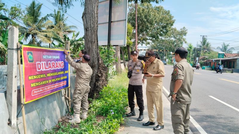 ANTISIPASI: Personel Satpol PP memasang spanduk larangan aktivitas anak jalanan.&nbsp;