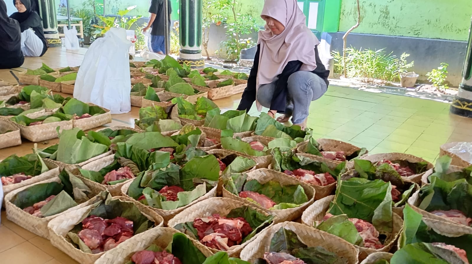 HIJAU : Panitia kurban Masjid Margoyuwono saat mengemas daging kurban menggunakan bahan ramah lingkungan seperti besek dan daun jati pada Jumat (6/6/2025). 